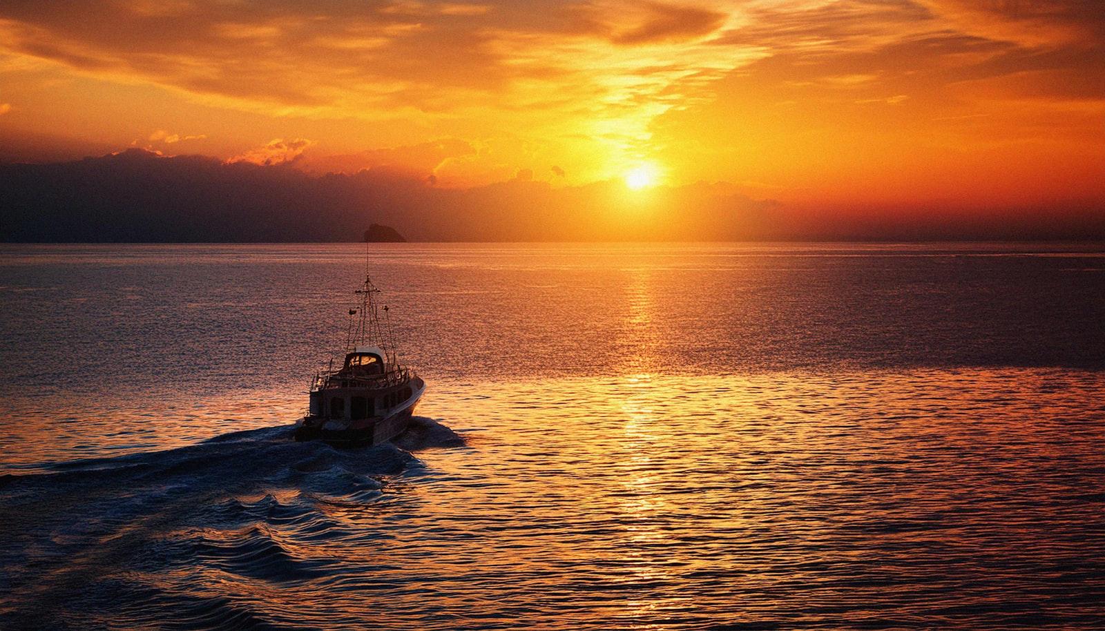 Boat cruising the harbor at sunset